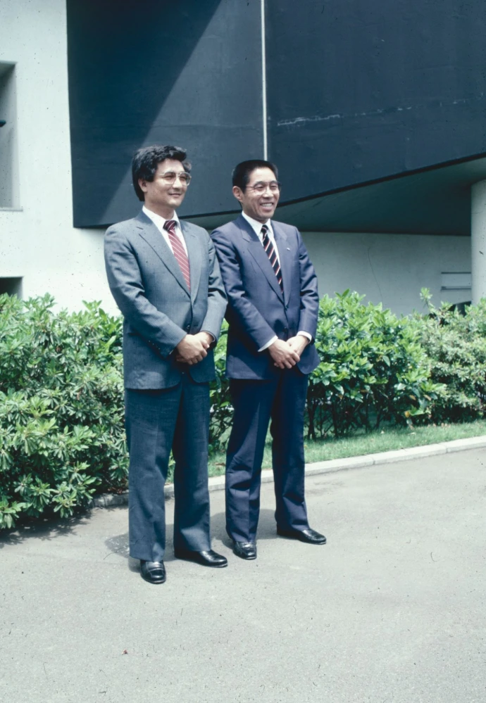 Two men standing next to each other in front of a building